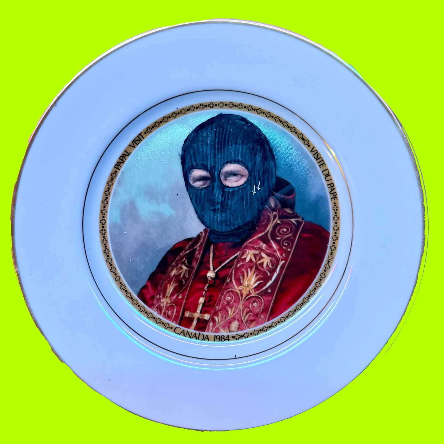 Decorative plate of the pope, painted to be wearing a balaclava, on a green background