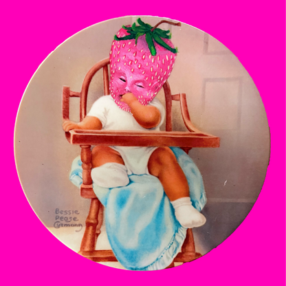 Decorative plate depicting a baby in a high chair painted to have a strawberry for a head. Plate is on a pink background.