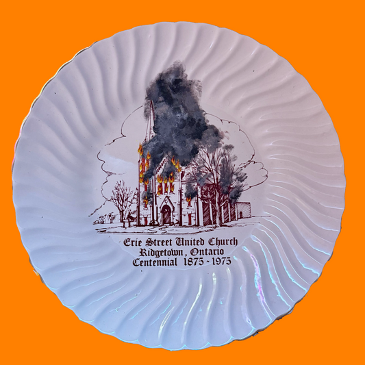 Decorative plate with a burning church illustration and text on an orange background
