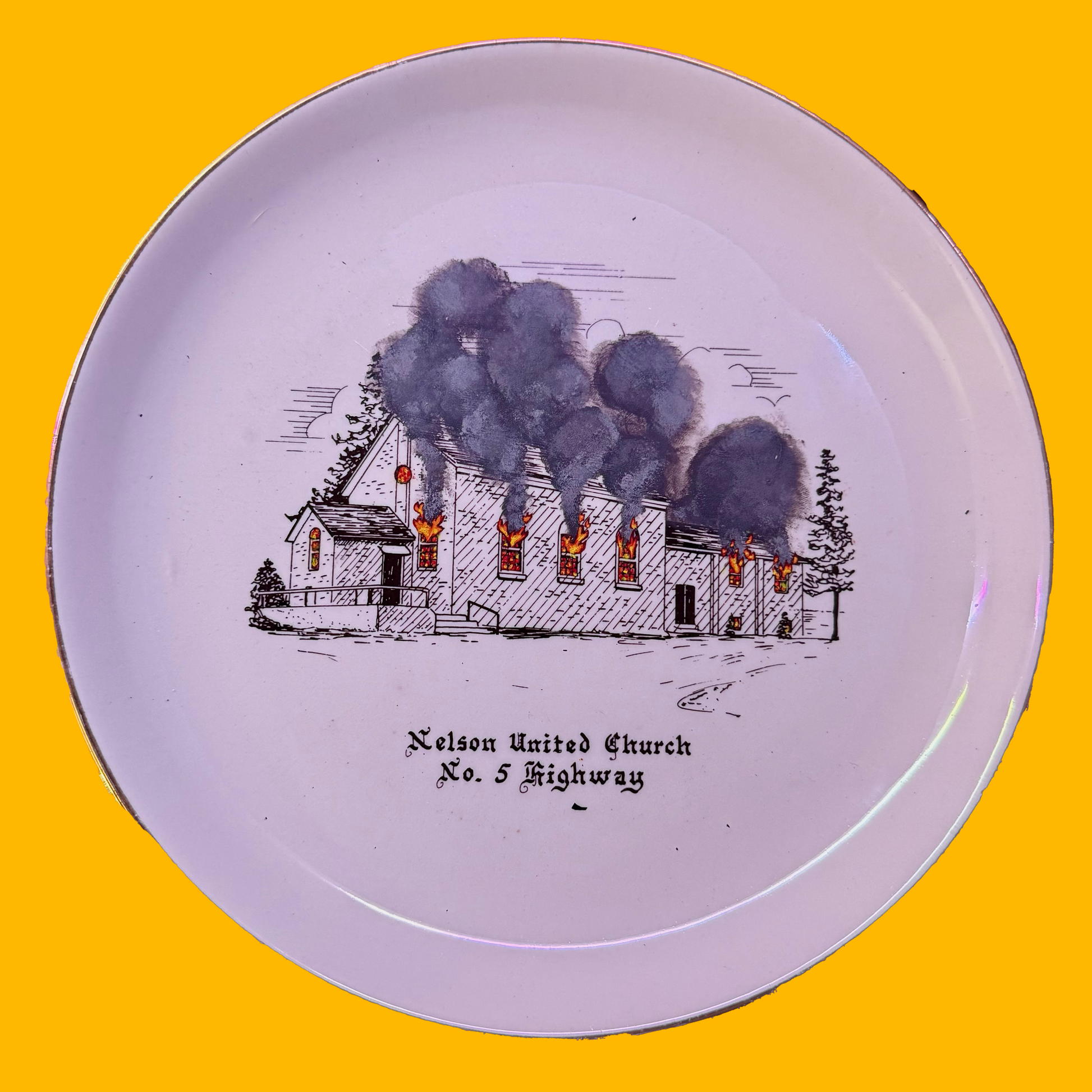 Plate with a black and white illustration of a burning church on a yellow background