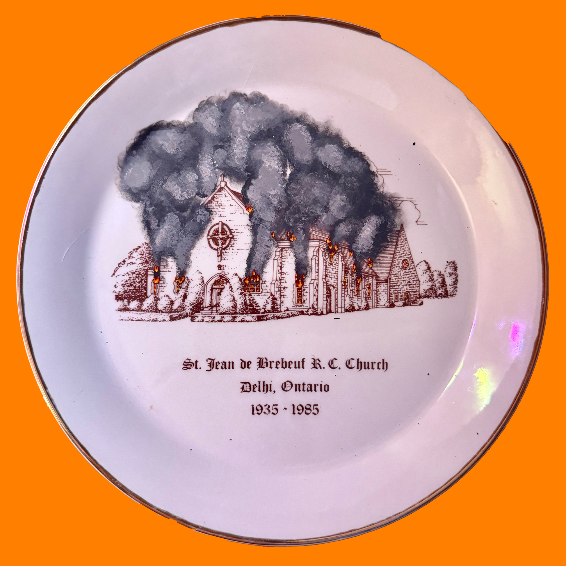 Decorative plate with a burning church illustration and text on an orange background