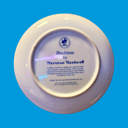 Decorative plate back with 'Bedtime' by Norman Rockwell written on it, on a blue background